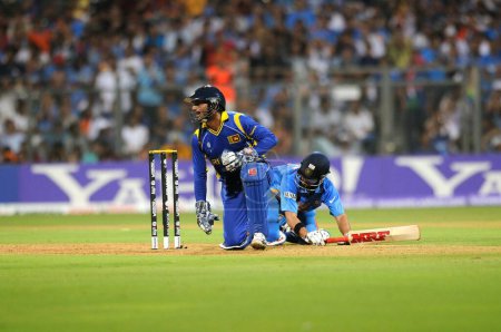Téléchargez les photos : Inde batteur Gautam Gambhir L atteint son pli lors d'une tentative de fuite par le capitaine sri-lankais gardien de guichet Sangakkara dans la finale de la Coupe du monde de cricket ICC 2011 match entre l'Inde et le Sri Lanka au stade Wankhede à Mumbai sur Ap - en image libre de droit
