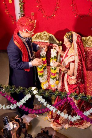 Téléchargez les photos : Mariée indienne et marié échangeant guirlande lors de la cérémonie de mariage - en image libre de droit