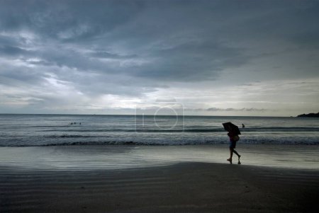 Téléchargez les photos : Une fille marchant avec un parapluie à la plage de Palolem ; Goa ; Inde - en image libre de droit