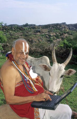 Téléchargez les photos : Sanskrit érudit ou sadhu avec ordinateur et vache melkote, karnataka, Inde - en image libre de droit