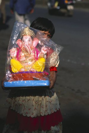 Foto de Niña sosteniendo estatua de Ganesh ganpati Festival Elefante cabeza Señor procesión, pune, Maharashtra, India - Imagen libre de derechos