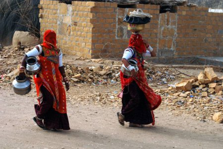 Téléchargez les photos : Deux femmes du village Rajasthani Marwari avec des pots vont bien chercher de l'eau, Khuhri, Jaisalmer, Rajasthan, Inde - en image libre de droit