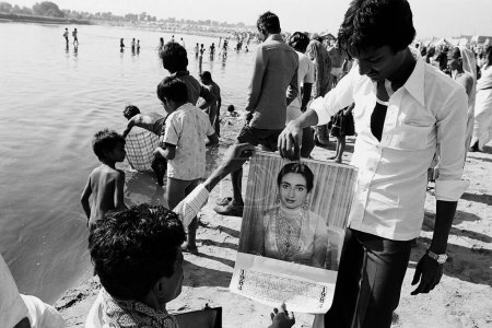 Téléchargez les photos : Homme montrant calendrier bollywood Foire de Vautha Gujarat Inde Asie 1983 - en image libre de droit