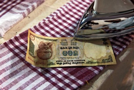Devotee ironing wet currency note offering to lalbaug cha raja after ganpati festival ; Bombay Mumbai ; Maharashtra ; India 5-September-2009
