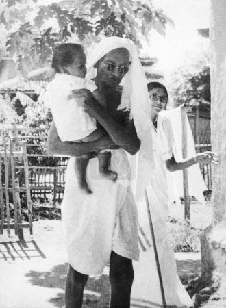 Foto de Mahatma Gandhi, llevando a Anand, hijo de Shardabehn Shukawala en el Ashram Sevagram, 1940 - Imagen libre de derechos