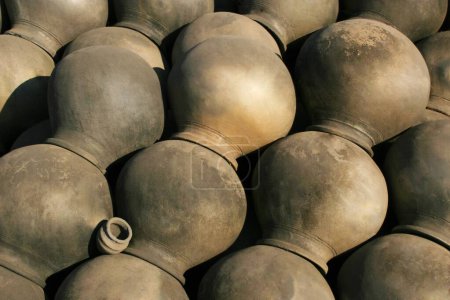 Abstract form of raw black earthen water pots stacked upside down with tiny one placed in between ; Pune ; Maharashtra ; India