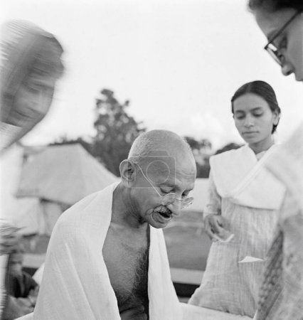 Foto de Mahatma Gandhi dando un autógrafo en su cumpleaños el 2 de octubre de 1944 en Pune, Rajkumari Amrit Kaur, Sohorabehn un ashramita - Imagen libre de derechos