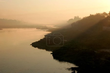 Téléchargez les photos : Filtrage matinal des rayons du soleil sur la rivière Mula ou Mutha ; Pune ; Maharashtra ; Inde - en image libre de droit