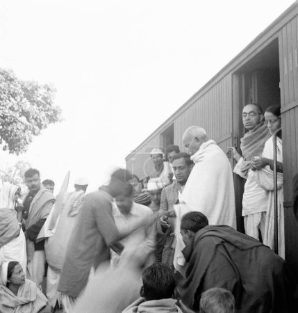 Foto de Mahatma Gandhi recogiendo donaciones para el fondo Harijan en una estación de tren en su camino a Assam, 1945, Ramkrishna Bajaj, Pyarelal Nayar y Prabhatibehn Jayaprakash - Imagen libre de derechos