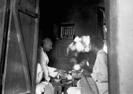 Téléchargez les photos : Mahatma Gandhi et Kaka Kalelkar r dans sa cabane à l'Ashram de Sevagram, 1946 - en image libre de droit