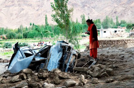 Téléchargez les photos : Femme regardant voiture endommagée en raison d'une inondation éclair dans saboo, Leh, Ladakh, Jammu-et-Cachemire, Inde - en image libre de droit