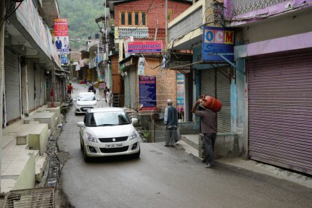 Foto de Hombre que lleva cilindro de GLP en la calle estrecha, ciudad de Banjar, valle de Tirthan, Kullu, Himachal Pradesh, India, Asia - Imagen libre de derechos