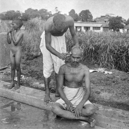 Téléchargez les photos : Vieux millésime 1900 noir et blanc image de l'homme chauve indien barbier tête de rasage Inde Années 1940 - en image libre de droit