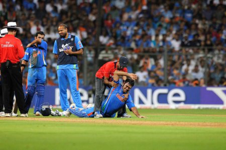 Téléchargez les photos : Le capitaine indien M S Dhoni reçoit un traitement de la part du physio lors de la finale de la Coupe du monde 2011 entre l'Inde et le Sri Lanka au stade Wankhede le 2 avril 2011 à Mumbai en Inde - en image libre de droit