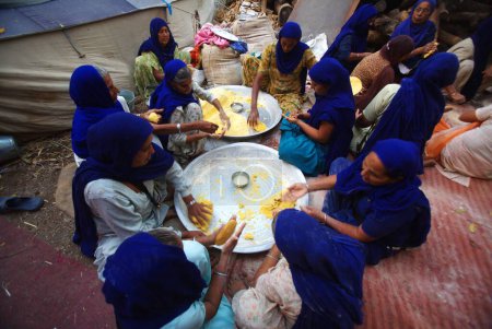 Foto de Devotos sij que preparan masa para hacer makai di rotis en la cocina comunitaria, 300º año de consagración del Guru perpetuo Granth Sahib, Sachkhand Saheb Gurudwara en Nanded, Maharashtra, India - Imagen libre de derechos