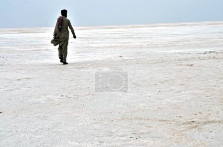 Photo for Man in pathani dress walking on salt residue at thar desert , Bhuj , Kutch , Gujarat , India - Royalty Free Image