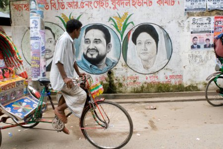 Téléchargez les photos : Cycle Rickshaw Rider passant près de chez Wall Painting Of Political Graffiti ; Dhaka ; Bangladesh - en image libre de droit