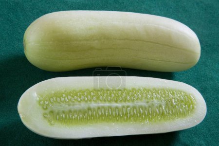 Photo for One full and half cut green vegetable Cucumber Kakdi on green background - Royalty Free Image