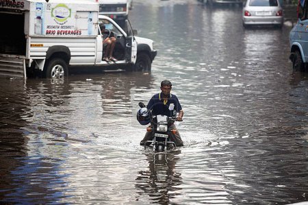Téléchargez les photos : Homme essayant de conduire à travers l'eau à Powai, Bombay, Mumbai, Maharashtra, Inde - en image libre de droit