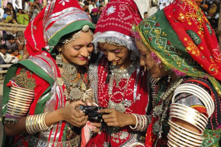 Foto de Chicas en joyería tradicional y traje de rajasthani mirando a la cámara, feria de Pushkar, Rajastán, India - Imagen libre de derechos