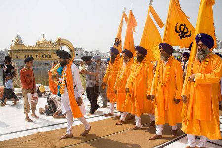 Photo for Orange color dressed Sikh men taking out the procession on the occasion of Guru Ramdas Jayanti out side Akal Takht, Swarn Mandir Golden temple, Amritsar, Punjab, India - Royalty Free Image