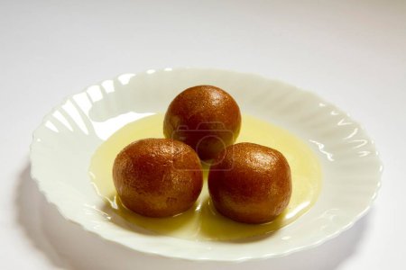 Photo for Indian sweet food three triple piece of round shape Gulabjamun Bonbon Confectionery with sugar syrup served in plate - Royalty Free Image