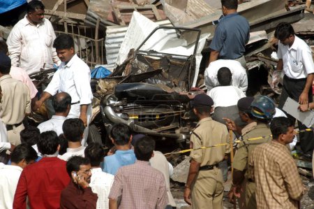 Téléchargez les photos : Des policiers de l'équipe de déminage inspectant des restes de taxi dans lequel l'explosion a eu lieu au bazar de Zaveri dans la zone occupée de Kalbadevi, Bombay Mumbai, Maharashtra, Inde, le 26 août 2003 - en image libre de droit