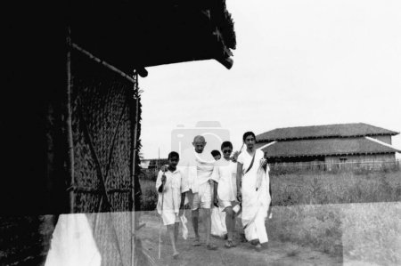 Foto de Mahatma Gandhi caminando con Abha Gandhi y Rajkumari Amrit Kaur en el Ashram Sevagram, 1940 - Imagen libre de derechos