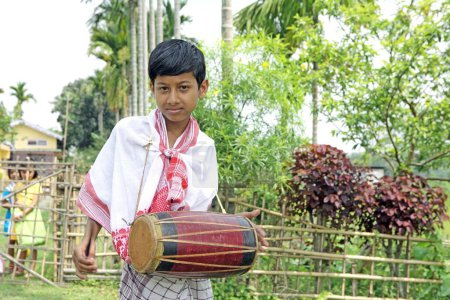 Téléchargez les photos : Garçon jouant d'un instrument de musique et célébrant le festival Bihu (célébration de la nouvelle année) Assam, Inde - en image libre de droit