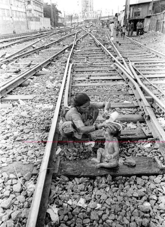 Photo for Mother bathing her son on railway tracks at Wadala, Bombay Mumbai, Maharashtra, India - Royalty Free Image
