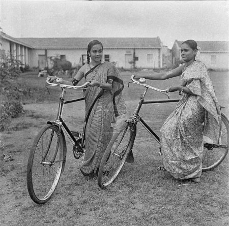 Photo for Old vintage 1900s black and white picture of Indian women girls cycles bicycles wearing sari India 1940s - Royalty Free Image
