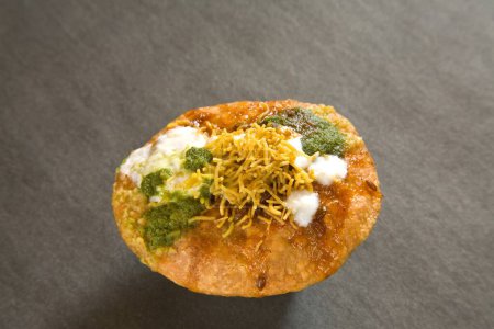 Foto de Snack indio frito shahi khasta kachori chaat con cilantro verde yogur y chutney de tamarindo con sev servido sobre fondo negro 23-abril-2010 - Imagen libre de derechos