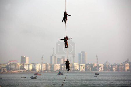 Photo for A mock drill of air lifting by a helicopter was conducted by the commandos at the Aerobatics show which was conducted by Sagar Pawan team of the Fly-In at Girgaum Chowpatty, Bombay Mumbai, Maharashtra, India - Royalty Free Image