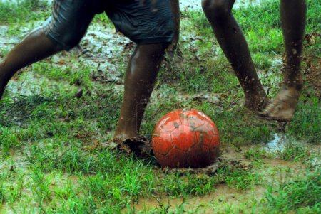 Foto de Los chicos indios del sur de Asia, jugando, disfrutando con la pelota a pie durante la temporada de monzones, India - Imagen libre de derechos
