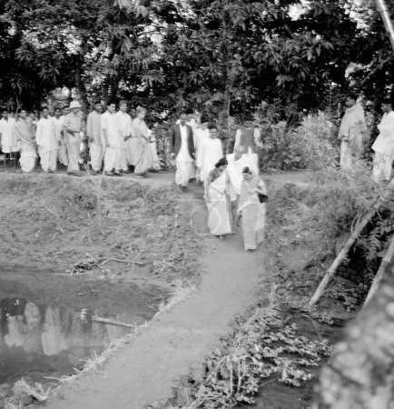 Photo for Mahatma Gandhi and his party passing a dam while being on the march through the area effected by Hindu Muslim riots in Noakhali East Bengal, November 1946, India - Royalty Free Image