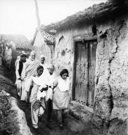Téléchargez les photos : Mahatma Gandhi, soutenu par Mridulabehn Sarabai et Manu Gandhi, marchant avec Khan Abdul Gaffar Khan et d'autres à travers un village des zones touchées par les émeutes du Bihar, 1947, Inde - en image libre de droit