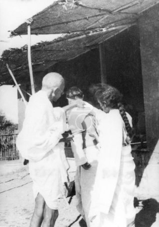 Photo for Mahatma Gandhi and Sushila Nayar treating Pyarelal Nayars hurting back who was bitten by a scorpion , at Sevagram Ashram , 1938 - Royalty Free Image
