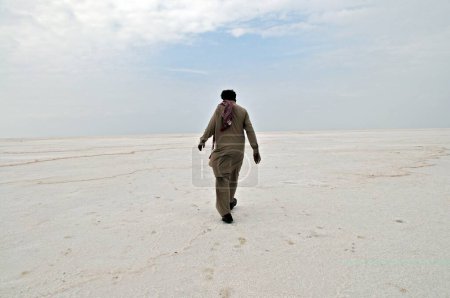 Foto de Hombre vestido de pathani caminando sobre residuos de sal en el desierto de Thar, Bhuj, Kutch, Gujarat, India - Imagen libre de derechos