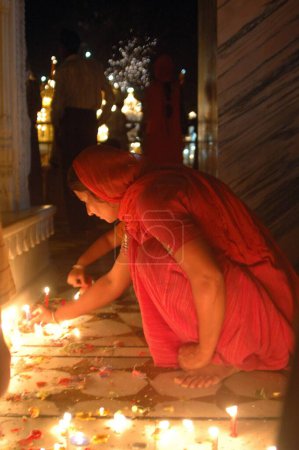 Foto de Mujer encendiendo lámparas de aceite para celebrar Baisakhi en el templo de oro; Amritsar; Punjab; India - Imagen libre de derechos