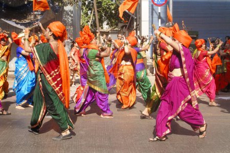 Photo for Maharashtrian lady wearing traditional nine yard sari with scarlet turban and playing Lazim drill ; celebrating Gudi Padva festival ; Thane ; Maharashtra ; India - Royalty Free Image