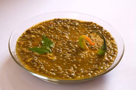 Indian masoor dal  red gram lentil soup garnish with curry leaves and chilli in glass bowl on white background