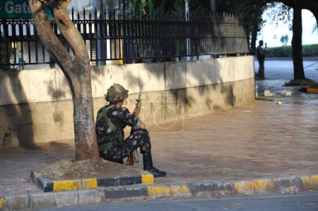 Photo for National Security Guard NSG commando taking position opposite Oberoi Trident hotel after terrorist attack by Deccan Mujahideen on 26th November 2008 in Bombay Mumbai ; Maharashtra ; India - Royalty Free Image