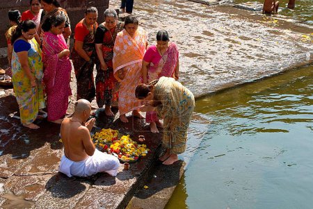 Téléchargez les photos : Personnes effectuant un rituel sur la rive de la rivière - en image libre de droit