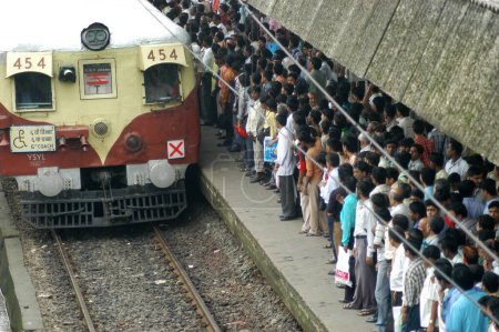 Photo for Commuters try to get into crowded local train during peak hour at Ghatkopar Railway Station in Bombay Mumbai, Maharashtra, India - Royalty Free Image
