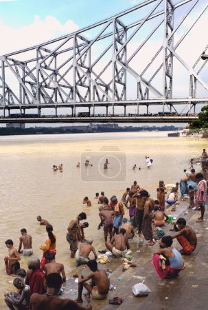 Photo for People bathing on ghat of hooghly river at Howrah bridge (Rabindra Setu) ; Calcutta now Kolkata ; West Bengal ; India - Royalty Free Image