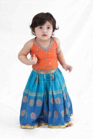 Fifteen month old baby girl in ghagra choli looking curiously 