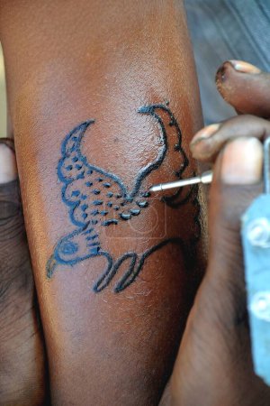 Hombre haciendo tatuaje de águila en su mano; Feria de Pushkar; Rajastán; India
