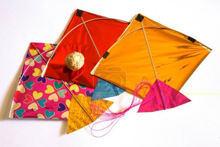 Téléchargez les photos : Fil de cerfs-volants colorés et laddoos doux tilgur ou til gul sésame pour Makara Sankranti festival sur fond blanc - en image libre de droit