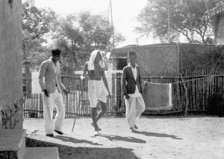 Téléchargez les photos : Mahatma Gandhi marchant avec deux hommes à l'Ashram de Sevagram, 1940 - en image libre de droit