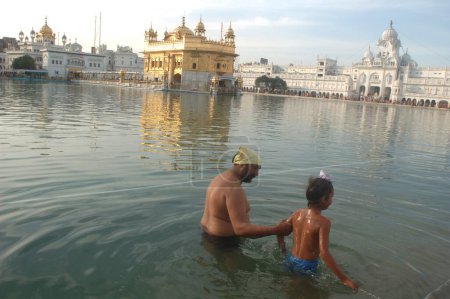 Téléchargez les photos : Les dévots sikhs prennent un bain sacré dans le sarovar Amrit le lac de nectar, temple d'or, Amritsar, Punjab, Inde - en image libre de droit